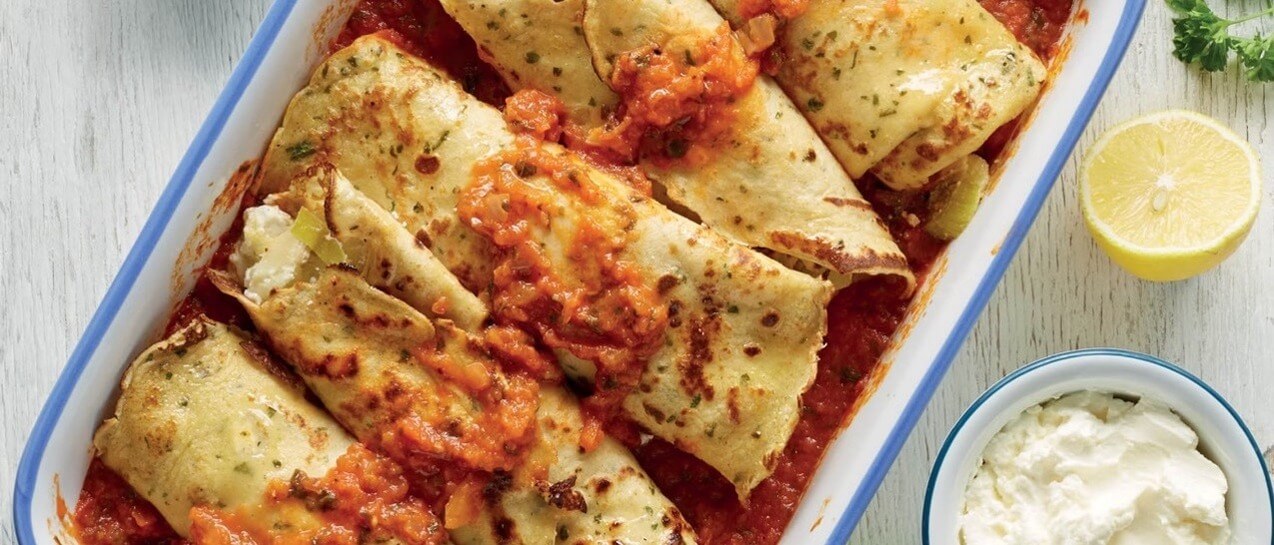 Image of savoury pancakes in a baking dish, with leeks, cheese and tomatoes.
